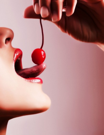 Mujer sacando la lengua y saboreando una cereza