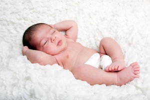 Fototgrafía de un bebé dormido en una tela que simula ser una nube