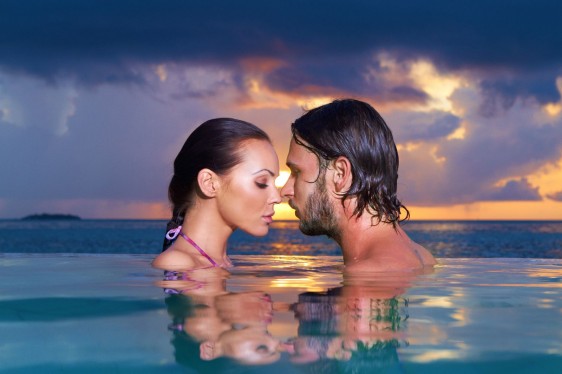pareja abrazandose en el agua con una playa en el fondo