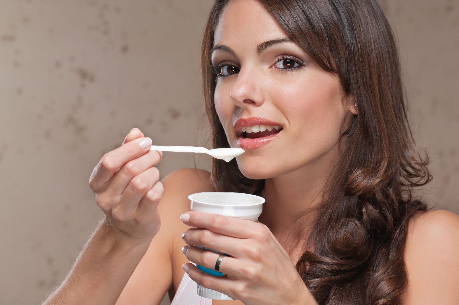 Mujer comiendo con una cuchara yogurt.