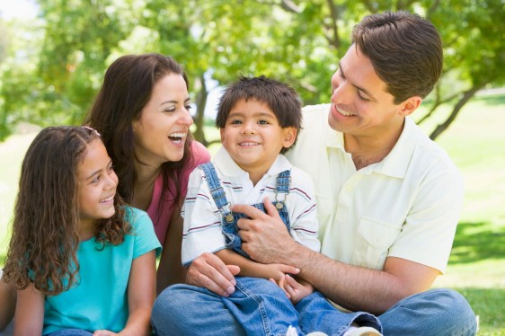 Familia sentada en un parque sonriendo