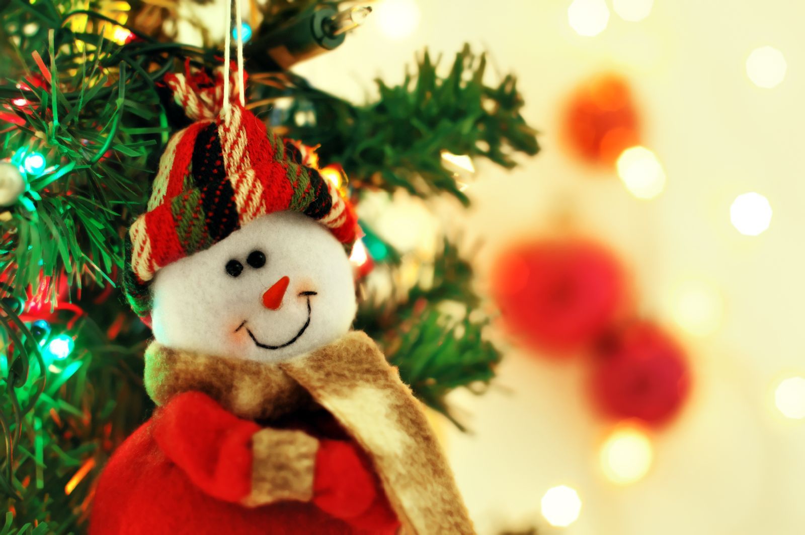 Muñeco de hombre de nieve sonriendo con árbol de navidad al fondo