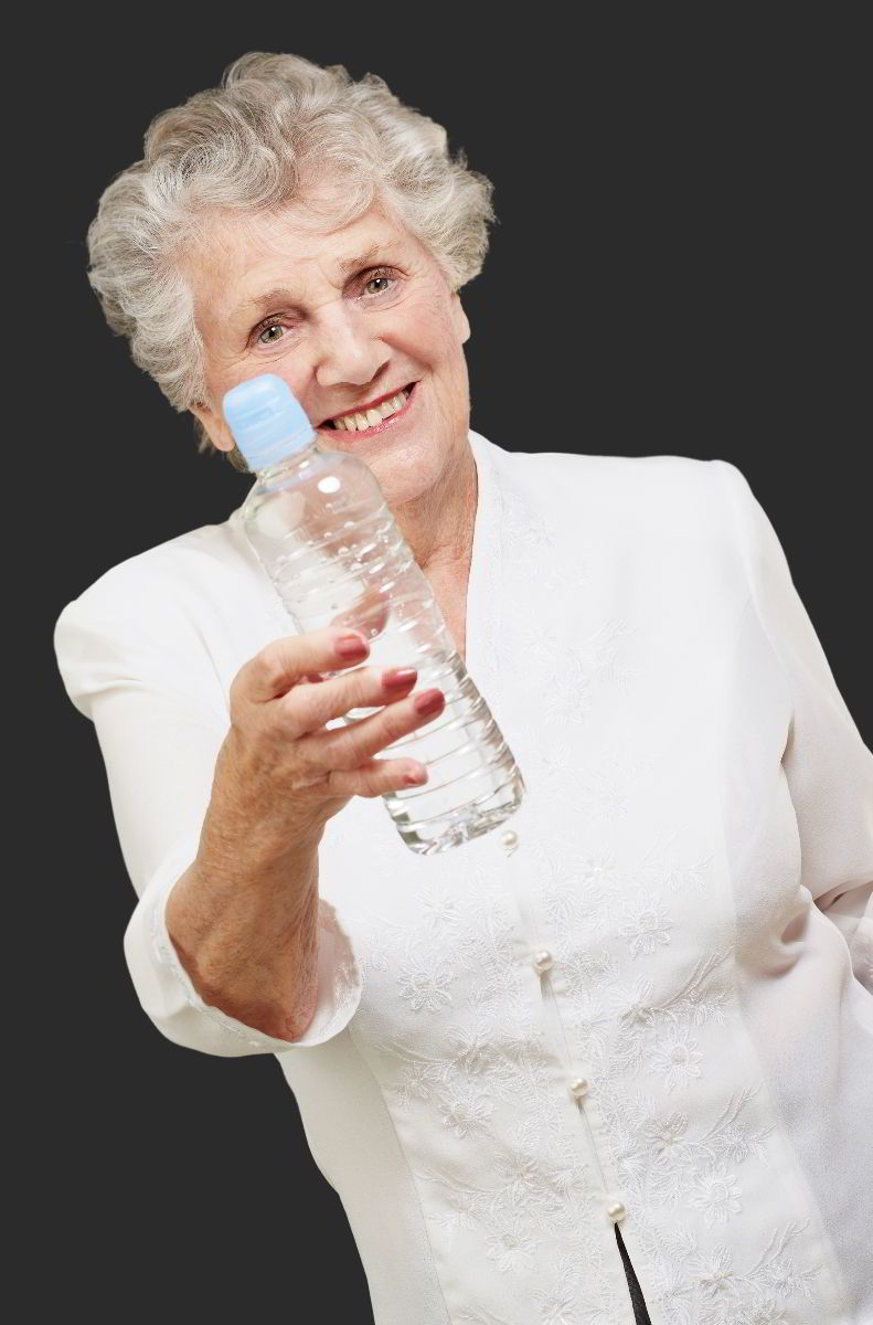 Mujer mayor vestida de vlanco con una botella de agua en la mano