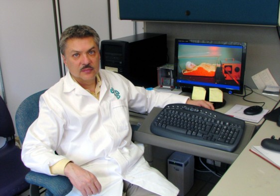 Alonso Fernández Guasti sentado al lado de una computadora personal de escritorio con un teclado en la mano izquierda