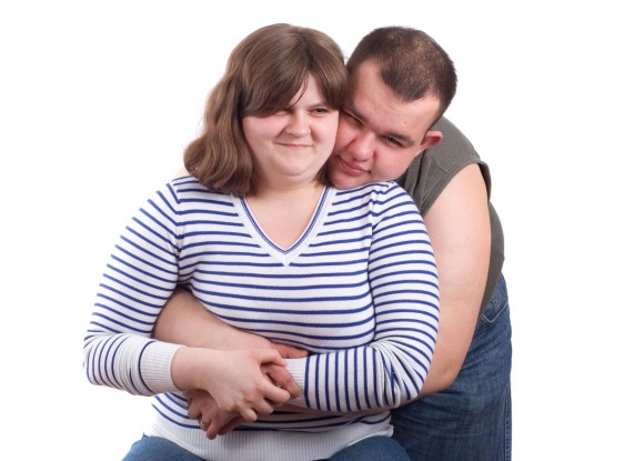 Hombre abrazando a mujer obesa con camisa azul a rayas