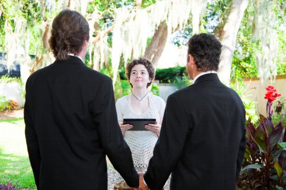 dos hombres vesitdos de negro frente a mujer vestida de blanco en una ceremonia de matrimonio