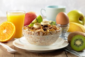 Plato de cereal con vaso de jugo de naranja platona kiwi y un huevo