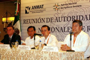Personas que representan autoriadades sanitarias sentadas en el fondo un anuncio con el lema "reunión de autoridades nacionales de América Latina "