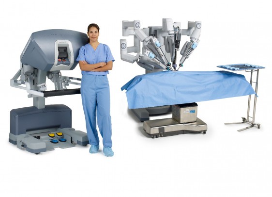 Cirujana de pie al lado del sistema sistema quirúrgico (consola, y mesa operaciones)