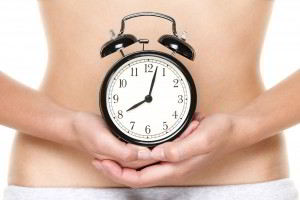Mujer sosteniendo reloj en el estomago