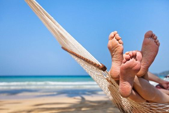 Acercamiento de los pies de una pareja en una amaca en la playa