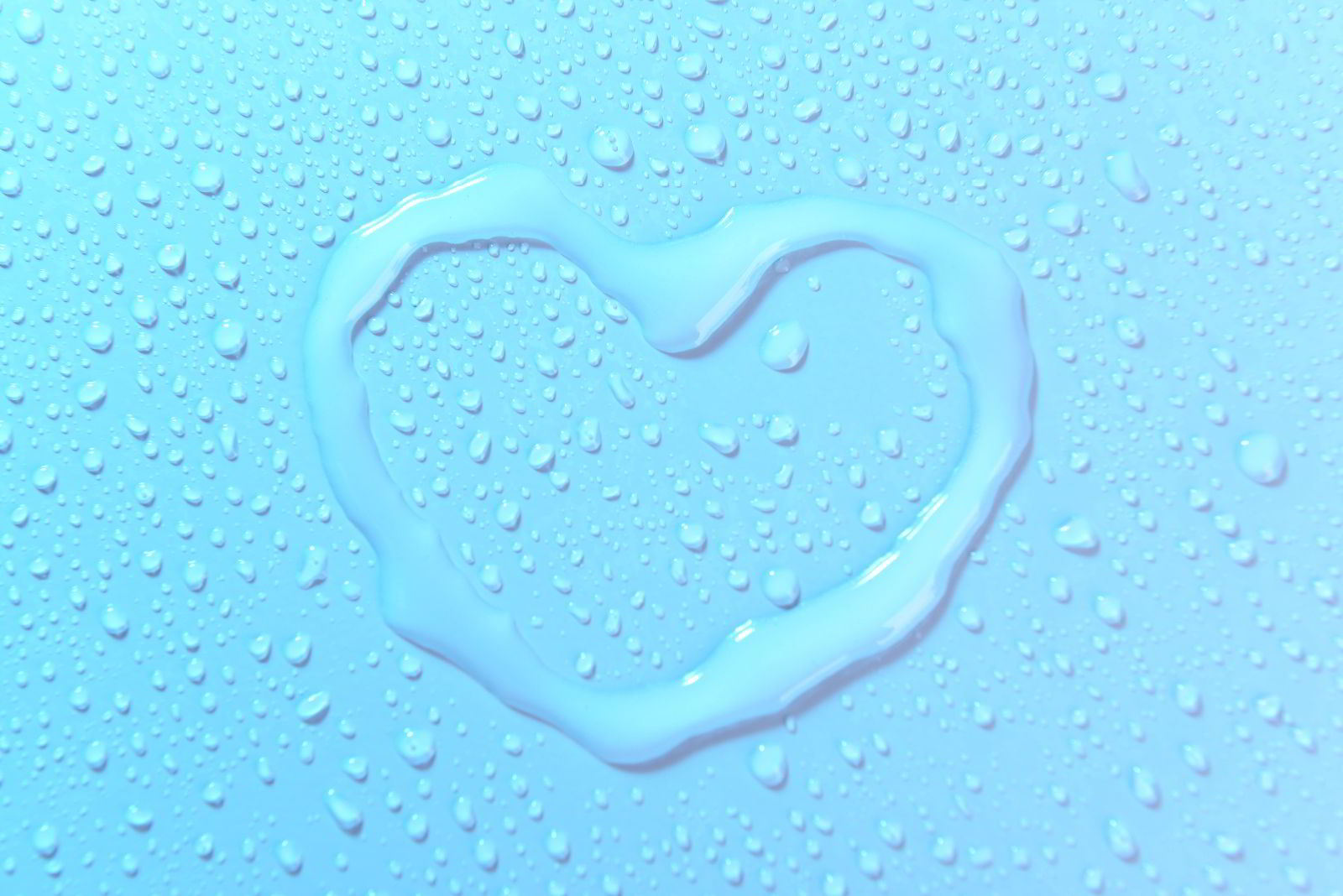 Un corazón dibujado con agua sobre una superficie azul