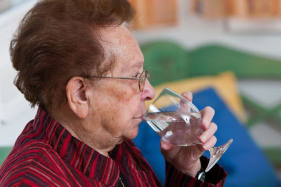 Mujer afulta mayor tomando un vaso con agua