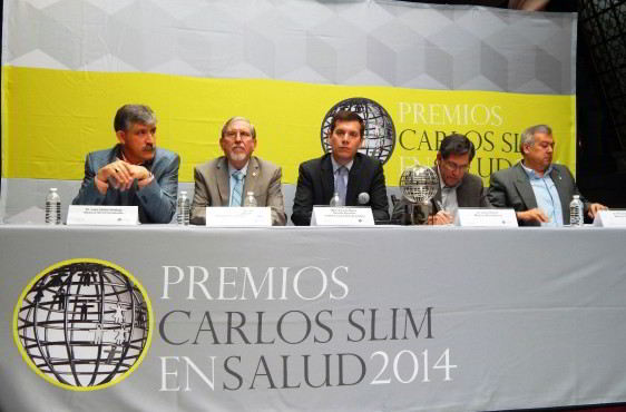 Ganadores del Premio en Salud 2014 sentados en una mesa con mantel que tiene los logotipos de Premios Carlos Slim en Salud 2014