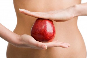 Mujer sostiene con una mano abajo y otra encima una manzana en su estomago