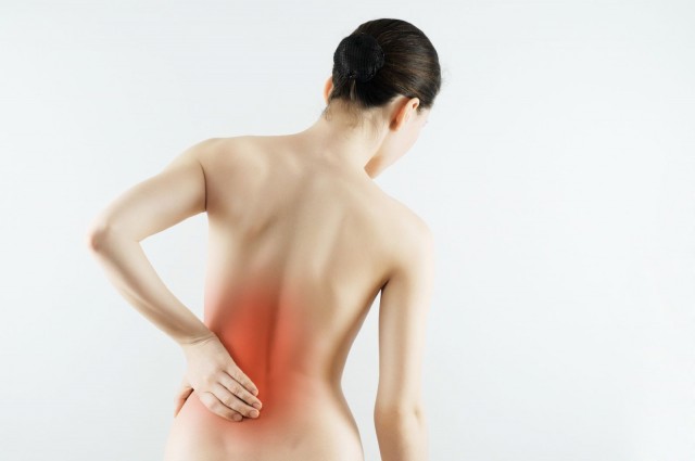 Mujer de espaldas tocandose la espalda baja marcada en tonaildad roja