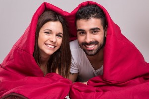 mujer y hombre debajo de ua sabana roja sonriendo