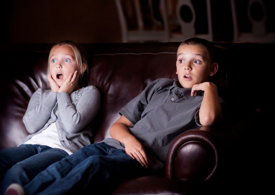 Dos niños observando en la oscuridad una televisión