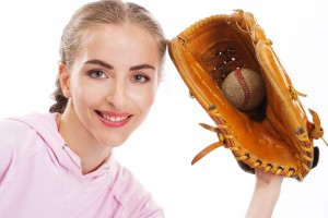 Mujer con sudadera rosa y guante de baseball en la mano, atrapando pelota