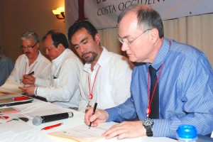 Grupo de personas sentadas y firmando documentos en una mesa