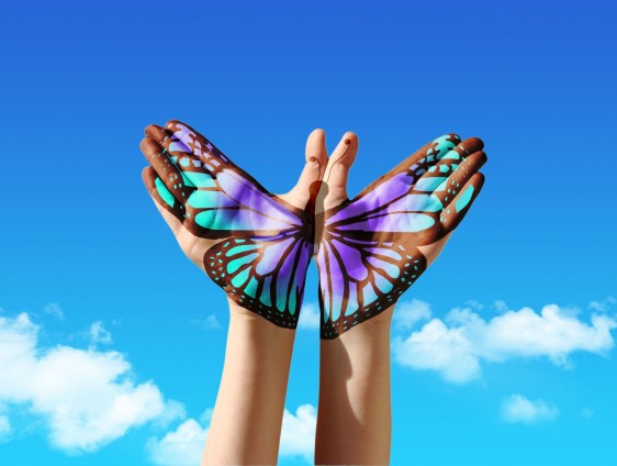Dos manos con dibujo de mariposa suimulando volar en el cielo