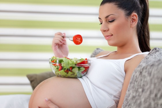 Mujer embarazada sentada con un plato de ensalada