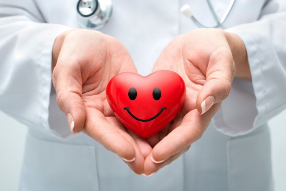 Acercamiento de un médico entre sus mano tiene un juguete en forma de corazón que tiene una sonrisa