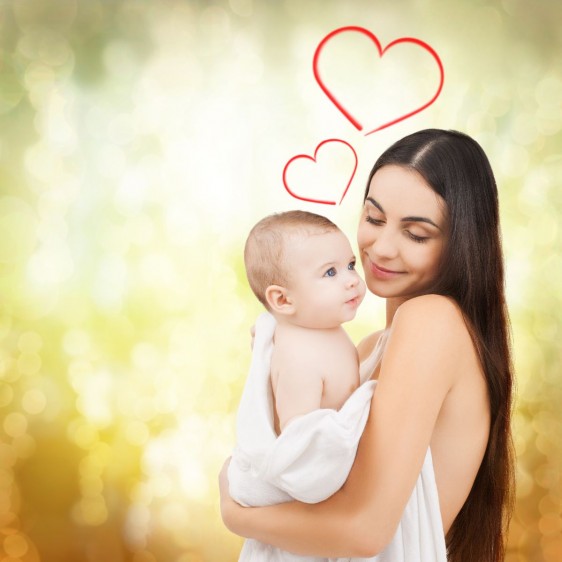 Madre abrazando a bebe con ilustración de corazones arriba de ellos al fondo tonalidades doradas