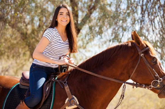 Mujer sonriendo montada en un caballo