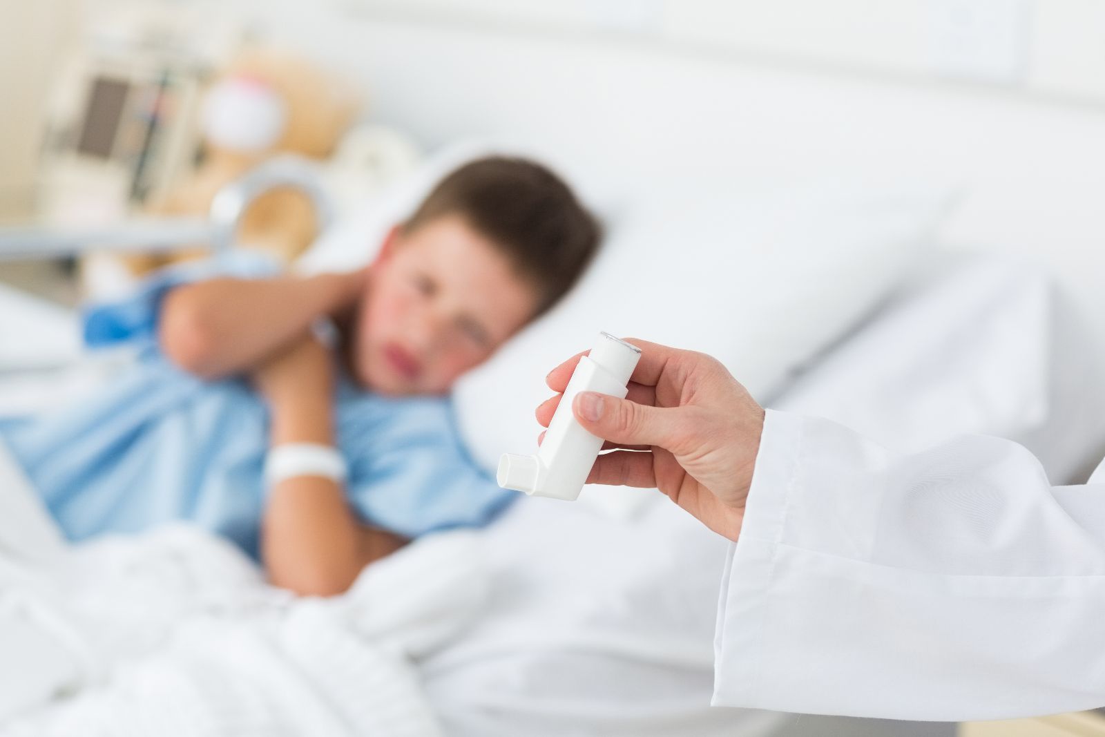 Mpedico sostiene dosificador en la mano al fondo un niño en cama