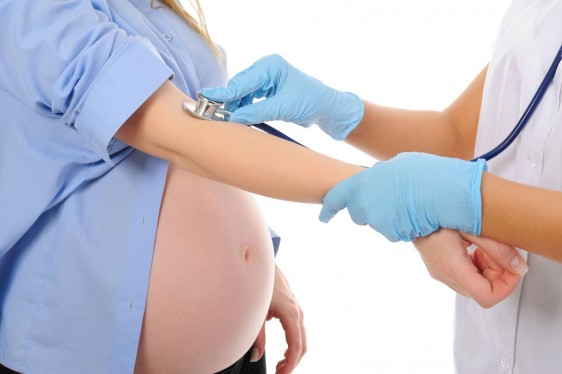 Acercamiento a la parte media de una mujer embarazada sido revisada por un médico con un estetoscopio