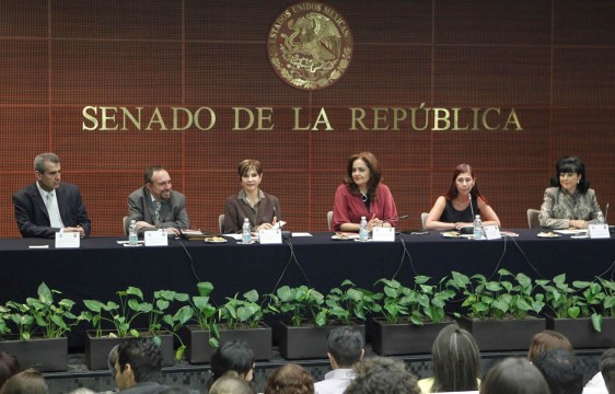 Grupo de personas sentadas en una mesa arriba de ellas la palabra Senado de la República