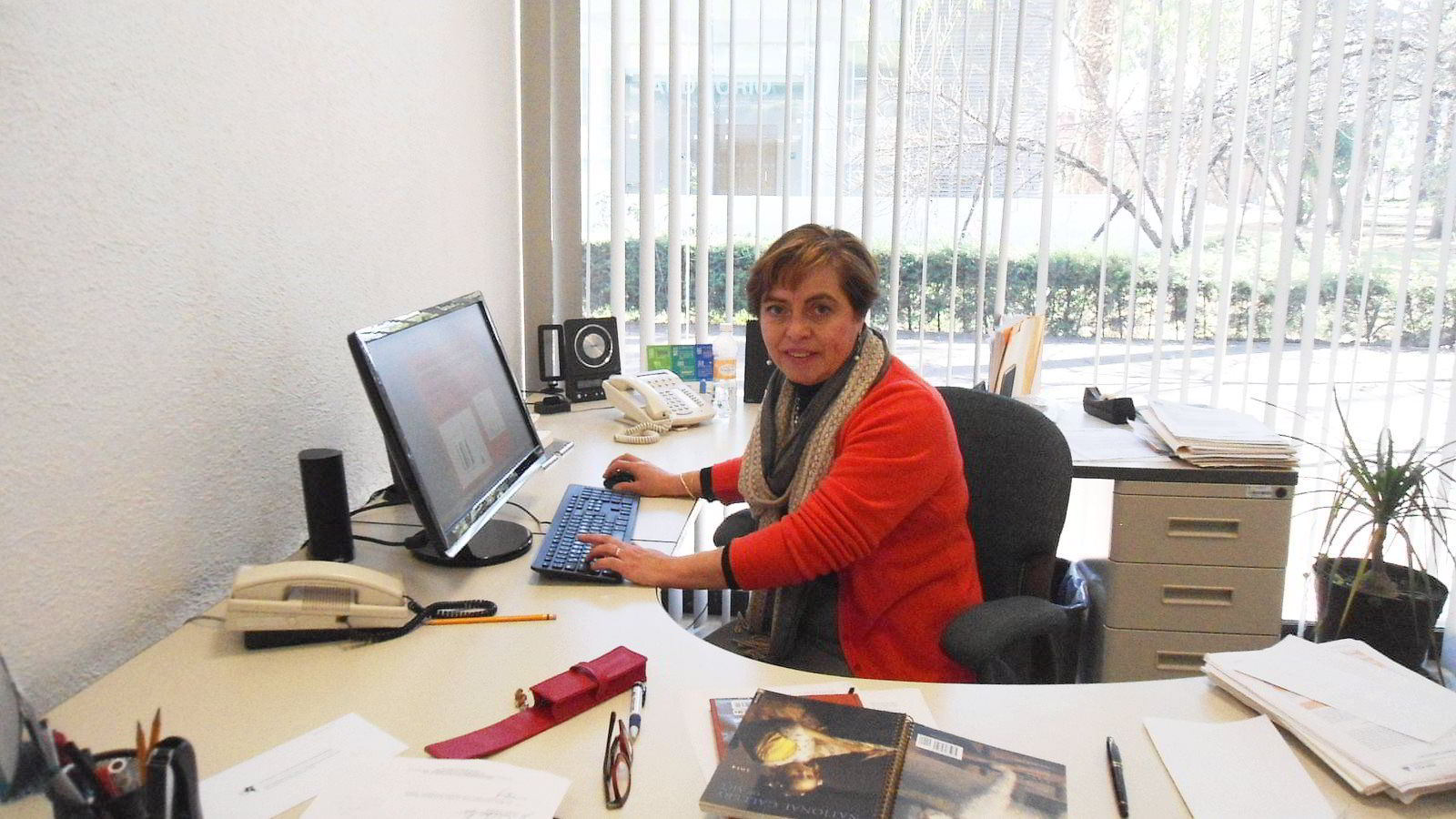 Doctora Gabriela Rodríguez Manzo sentada en un escritorio engfrente de una pantalla de computadora