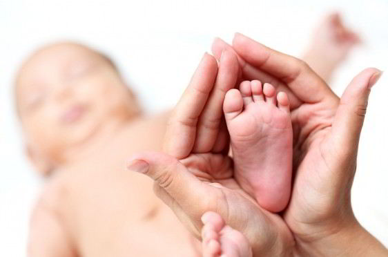 Acercamiento al pie de un recién nacido en las manos de una mujer