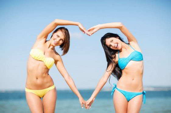 Dos mujeres en la playa haciendo con su cuerpo un corazón