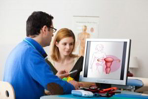 Un ginecólogo observando una ilustración en una pantalla con una mujer
