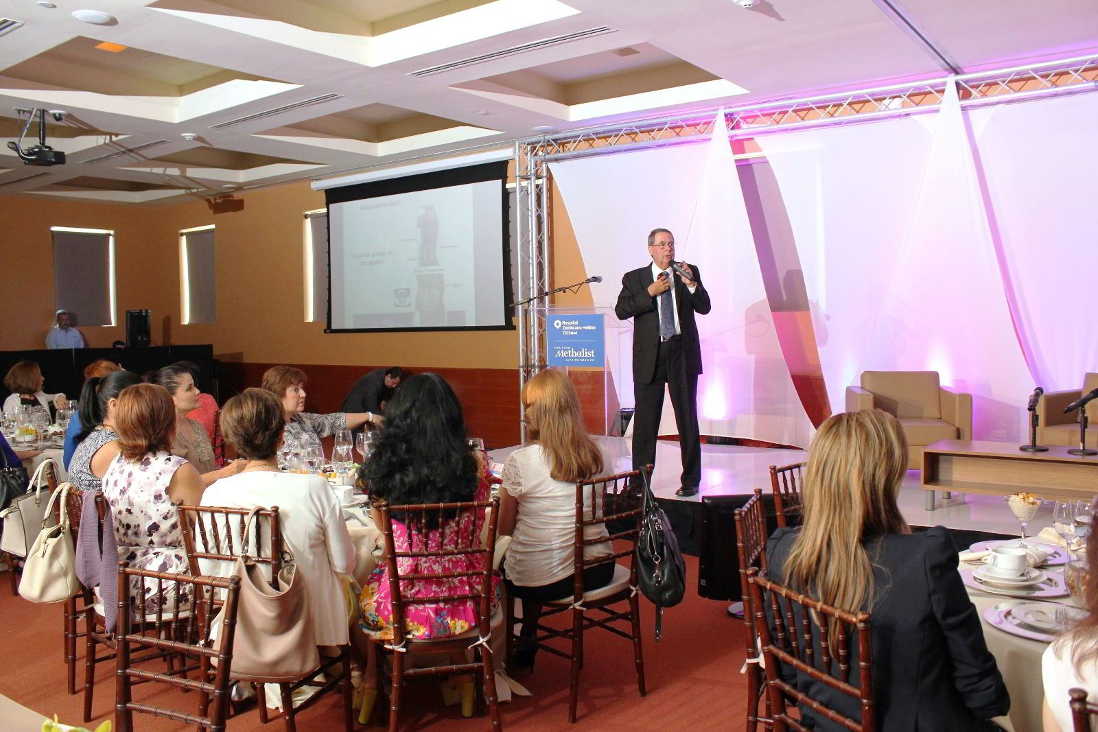 Colin M. Barker, exponiendo en un foro en una sala con mujeres