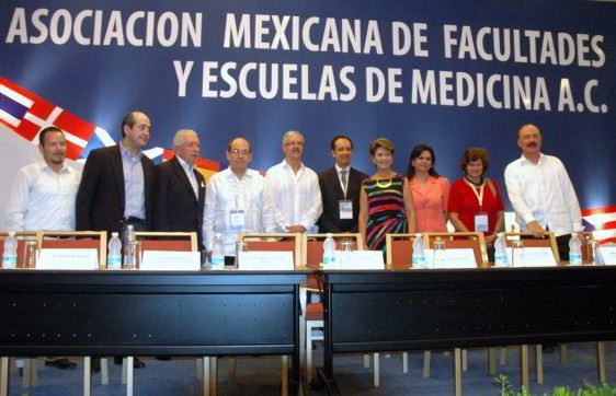 Personas de pie atras un letrero con e texto Asociación Mexicana de Facultades y Escuelas de Medicina
