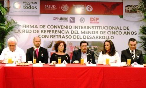 Grupo de funcionarios sentados en una mesa atras un letrero con el texto convenio de Red de Referencia y Contrarreferencia de la Estrategia de Desarrollo Infantil