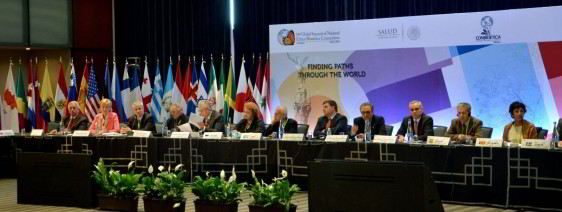 Personas sentadas en una sala atrás banderas de países y letrero "10 Cumbre Global de Comisiones Nacionales de Ética y Bioética" 