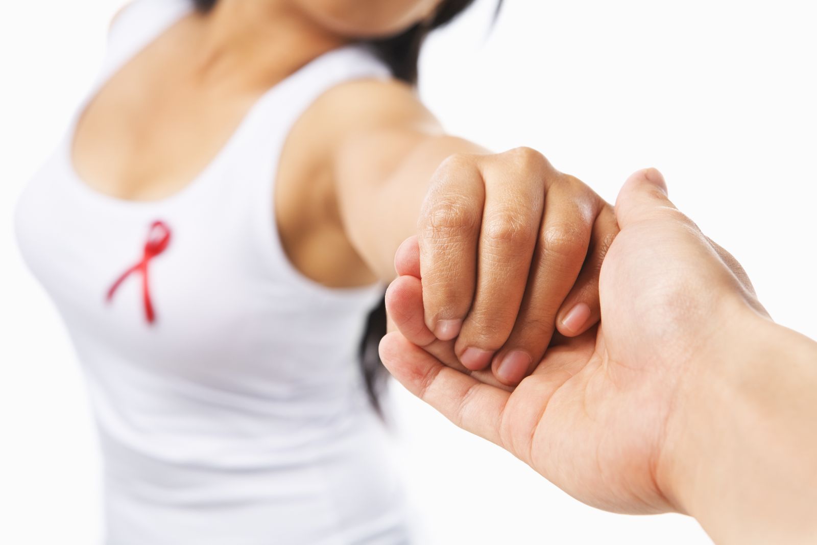 Mujer dando la mano a otra en el pecho con un listón rojo