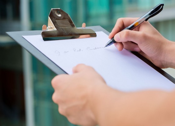 Persona escribiendo sobre una tabla con sujetador de documentos