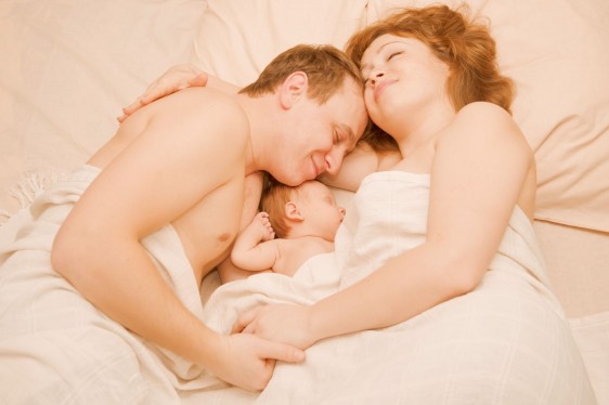 Padre, Madre y bebé juntos durmiendo en una cama