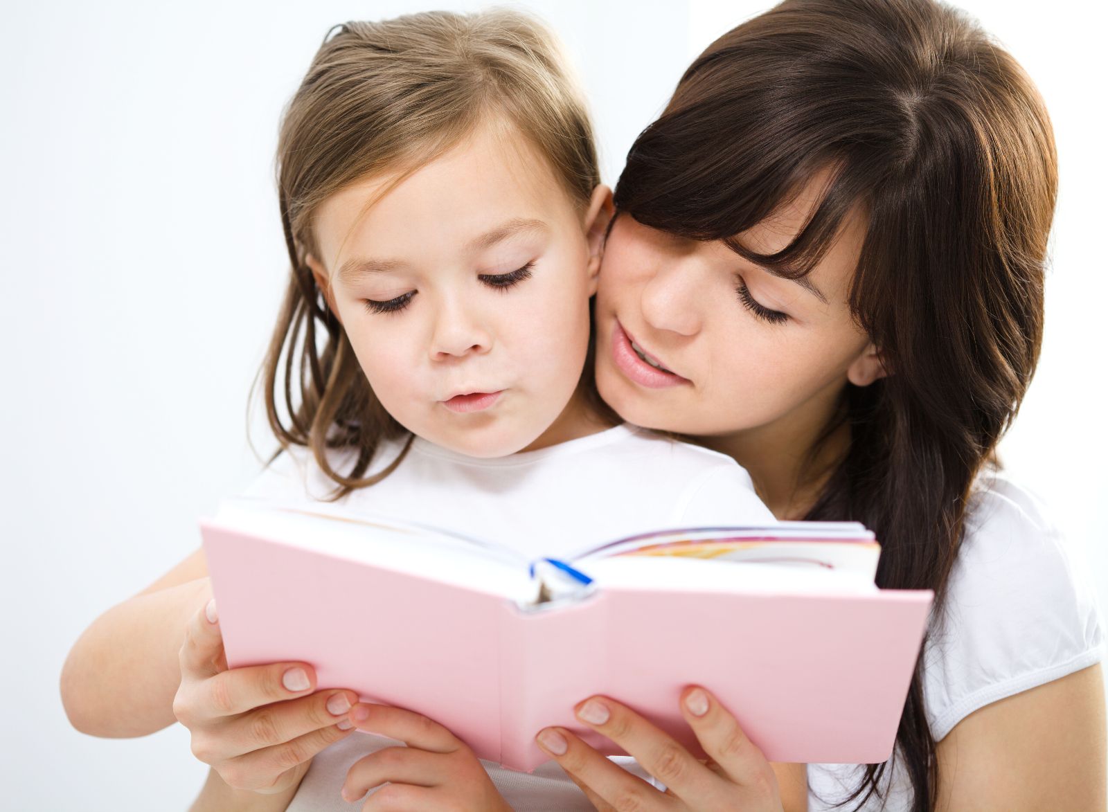 Madre recargada con hija que se encuentra leyendo