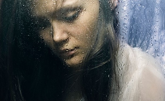 Mujer mirando la lluvia en una ventana