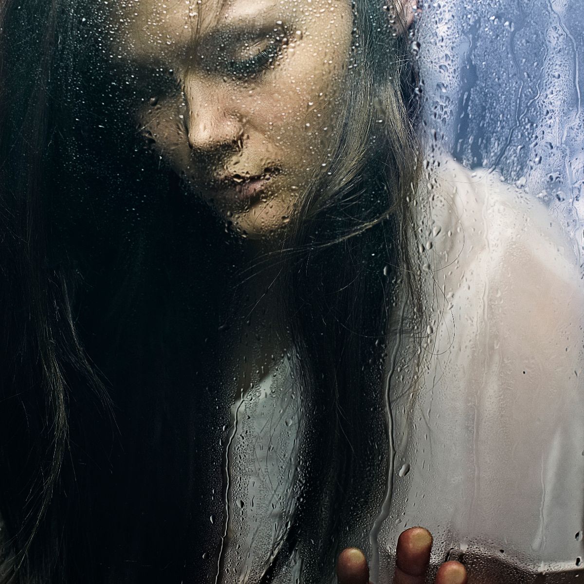 Mujer mirando la lluvia en una ventana