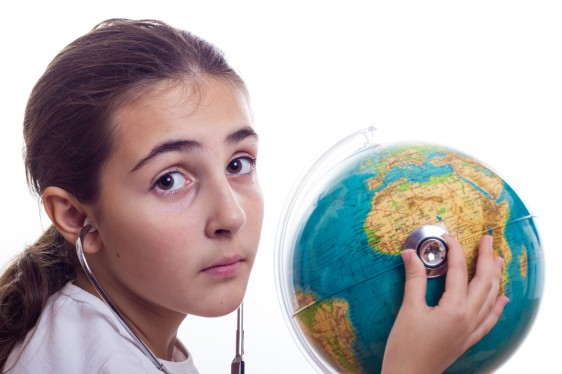 Niña escucha con estetoscopio a un globo terraqueo