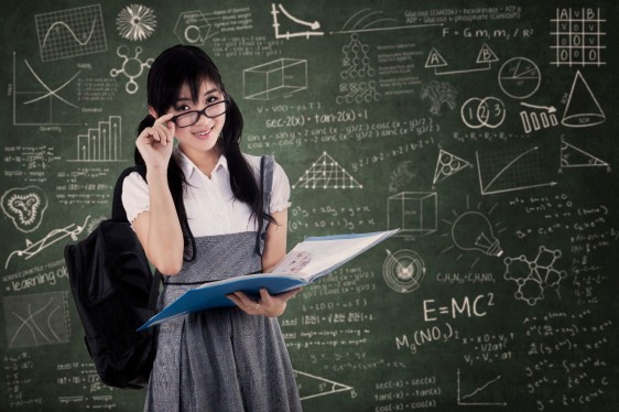 Adolescente con lentes al fondo un pizarrón con formulas y datos escolares