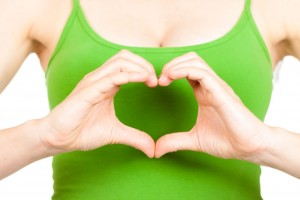 Mujer con camiseta verde hace con sus manos un símbolo de corazón