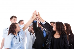 Grupo de médicos y personas en traje alzando las manos y tocando un punto común